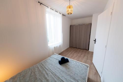 a room with a bed with a black shoe on it at KASA ZEN - Climatisation - Tout équipé - Stationnement gratuit in Saint-Chamond