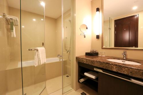 a bathroom with a shower and a sink and a mirror at Evergreen Laurel Hotel, Shanghai in Shanghai