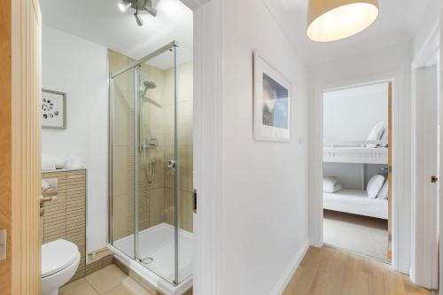 a white bathroom with a shower and a toilet at The Hawthorns in Polzeath