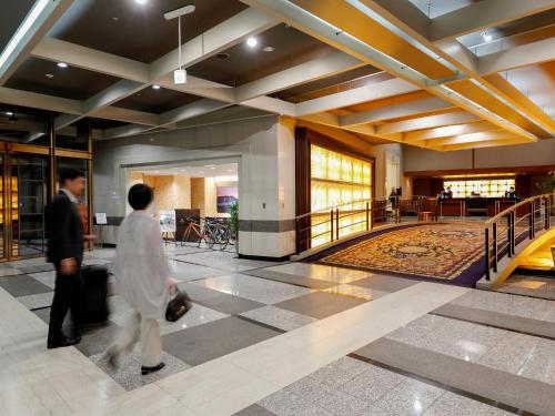 a man and woman walking through a lobby at Premier Hotel -Tsubaki- Sapporo in Sapporo