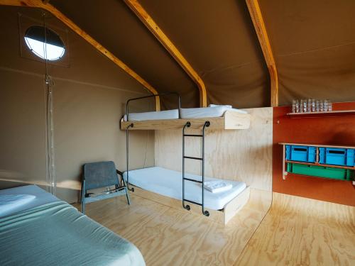 a room with two bunk beds and a chair at Vakantiepark De Klepperstee in Ouddorp