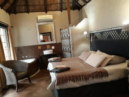 a bedroom with a bed and a chair and a mirror at African Silhouette Guesthouse in Benoni