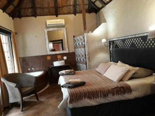 a bedroom with a bed with a chair and a mirror at African Silhouette Guesthouse in Benoni