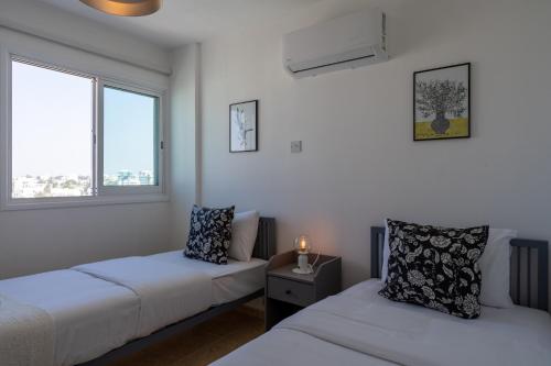 2 camas en una habitación con 2 ventanas en Chloris 3- Bedroom Apartment W/Pool in Larnaca, en Lárnaca