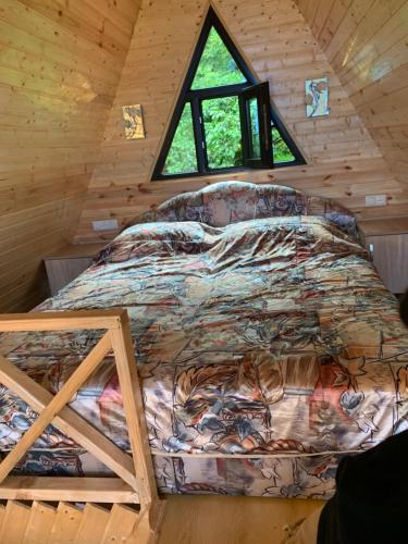 a bed in a log cabin with a window at Eco house ketevani in K'obulet'i