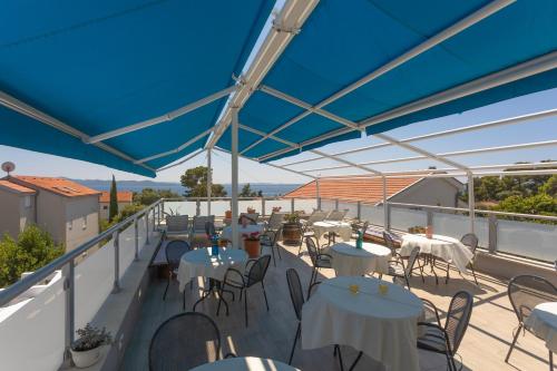 a balcony with tables and chairs and a blue canopy at Pansion Pirat in Petrcane