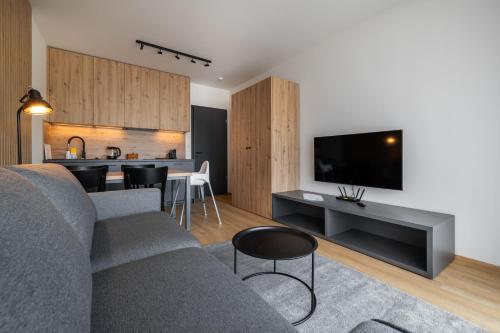 a living room with a couch and a tv and a kitchen at Apartmány Florián in Kvilda