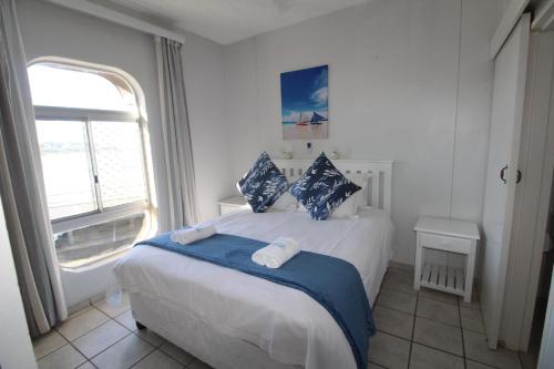 a bedroom with a bed with blue pillows and a window at Seagull 303 in Margate