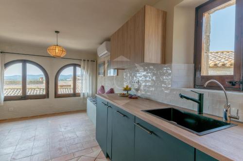 a kitchen with blue cabinets and a sink and windows at PALS - Maison médiévale tout confort in Pals