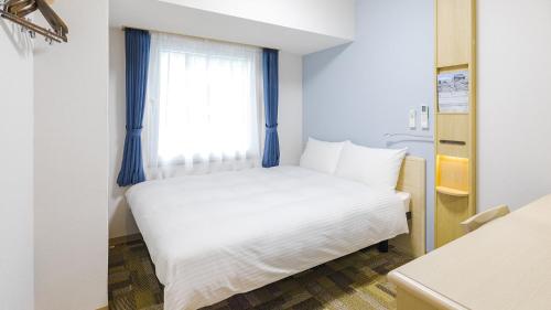 a white bed in a room with a window at Toyoko Inn Futamatagawa-eki Kita-guchi in Yokohama