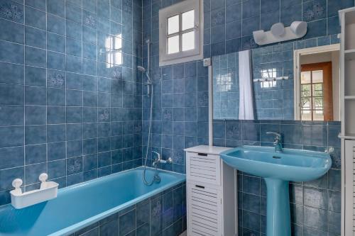 La salle de bains bleue est pourvue d'un lavabo et d'une baignoire. dans l'établissement Maison pour 10 tout près de la plage à Sarzeau, à Sarzeau