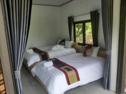 two twin beds in a room with a window at Dong Suoi H'mong Homestay & Bungalow in Mù Cang Chải