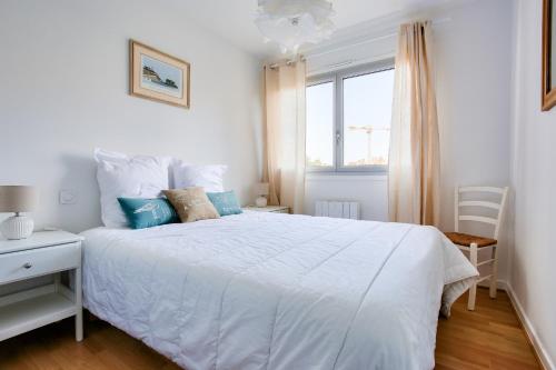 a white bedroom with a white bed and a window at Appartement pour 4 avec vue mer à Pléneuf in Le Val-André