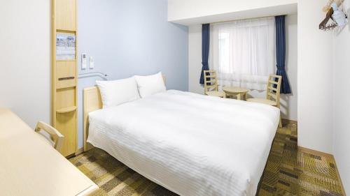 um quarto com uma grande cama branca e uma mesa em Toyoko Inn Futamatagawa-eki Kita-guchi em Yokohama