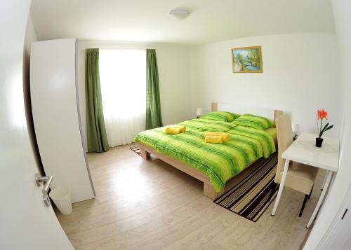 a bedroom with a green bed and a window at Apartments Žugec in Seliste Dreznicko