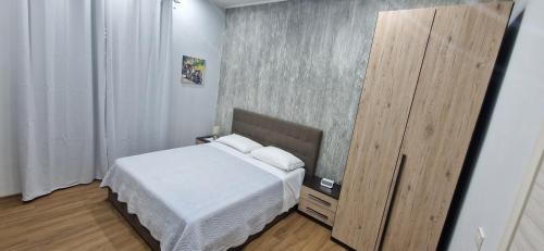1 dormitorio con cama blanca y armario de madera en B&B Mongibello, en Viagrande