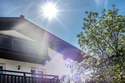 a sun shining on a house with a tree at Haus Wasmer by AlpenTravel in Bad Hofgastein