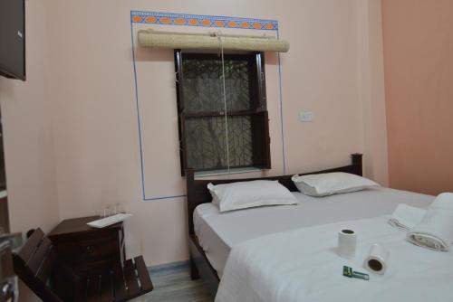 a bedroom with two beds and a window and a desk at Hotel Bawarri Haveli in Jodhpur