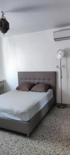 a bed in a white room with a lamp at Maison de la plage in Valras-Plage