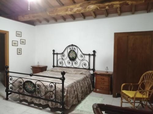 um quarto com uma cama preta e uma cadeira em Casetta in campagna. Bilocale con veranda em Scansano