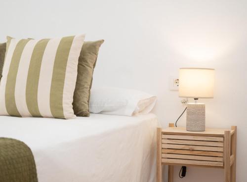 Un dormitorio con una cama y una lámpara en una mesita de noche. en SibsSanlucar Duquesa Loft Coqueto Ideal Parejas, en Sanlúcar de Barrameda