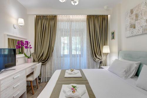 a bedroom with a bed and a desk and a television at Artemisia Villa with Outdoor Hot Tub, Sani Luxury Villas collection in Sani Beach