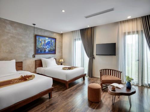 a hotel room with two beds and a tv at Draha Halong Hotel in Ha Long