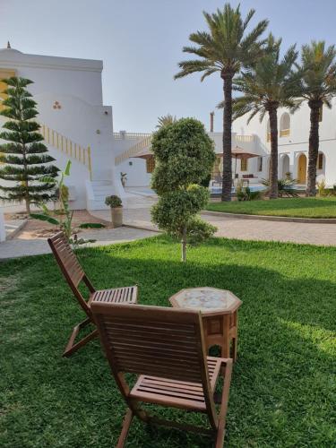 a chair and a table in a yard with palm trees at Dar El Jerbi in Mezraya