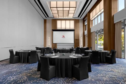 a conference room with tables and chairs and a screen at Clark Marriott Hotel in Clark
