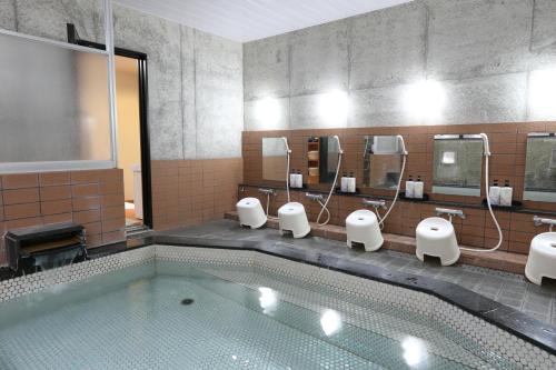 ein Badezimmer mit einem Pool, Waschbecken und Spiegeln in der Unterkunft Snowlines Lodge Hakuba in Hakuba
