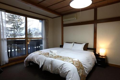 a bedroom with a bed and a large window at Snowlines Lodge Hakuba in Hakuba