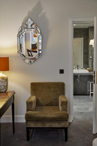 un salon avec une chaise et un miroir dans l'établissement Hôtel du Danube Saint Germain, à Paris