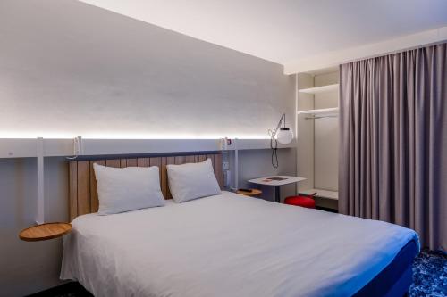 1 dormitorio con 1 cama blanca grande con almohadas blancas en ibis La Rochelle Centre Historique, en La Rochelle