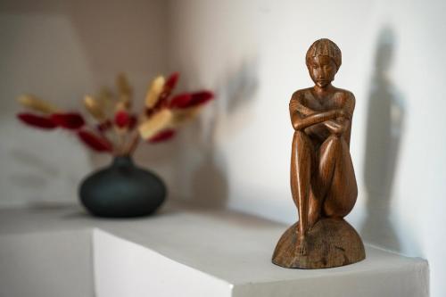 a small wooden figurine sitting on a table with a vase of flowers at Villa Falcone in Alvignano