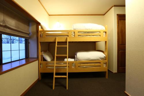 a bunk bed room with two bunk beds and a ladder at Snowlines Lodge Hakuba in Hakuba