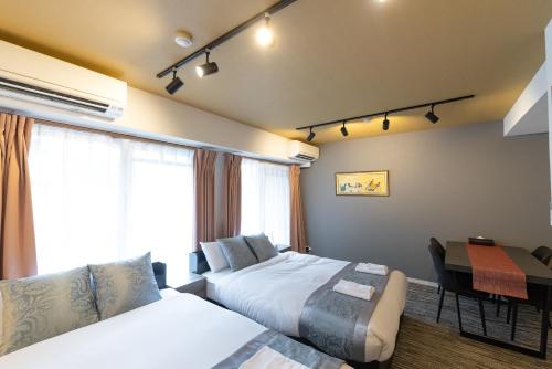 a bedroom with two beds and a table and a desk at F cross EBISU in Osaka
