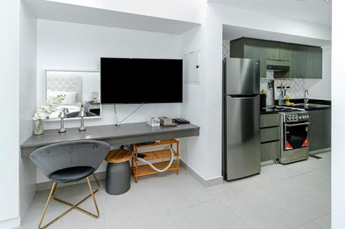 a kitchen with a desk with a tv and a refrigerator at Modern Studio with Pool & Gym Access in Dubai