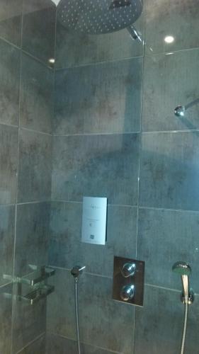 a shower with a glass door with a sign on it at Hôtel de La Cloche in Dole