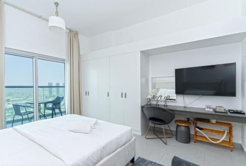 a bedroom with a bed and a desk with a television at Modern Studio with Pool & Gym Access in Dubai