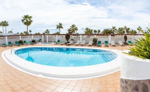 a pool at a resort with chairs at KALIMA APARTMENT in Puerto del Carmen