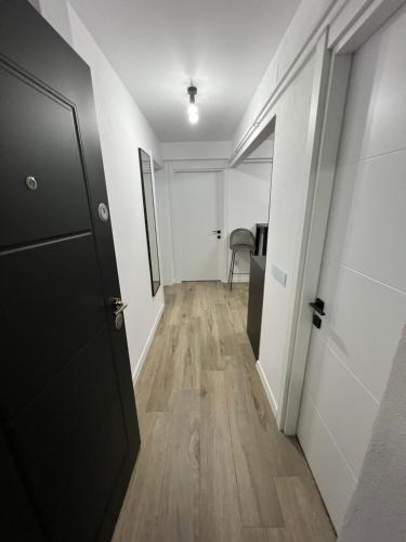 um corredor com uma porta preta e pisos de madeira em Onix em Hunedoara