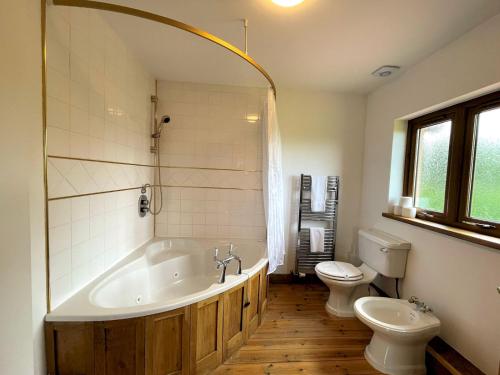 a bathroom with a large tub and a toilet at Pass the Keys Spectacular 7BR House Hot Tub and Gardens in Gretna in Gretna Green