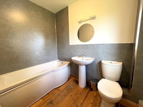 a bathroom with a sink and a toilet and a bath tub at Pass the Keys Spectacular 7BR House Hot Tub and Gardens in Gretna in Gretna Green