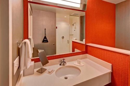 a bathroom with a sink and a large mirror at Courtyard by Marriott Westbury Long Island in Westbury