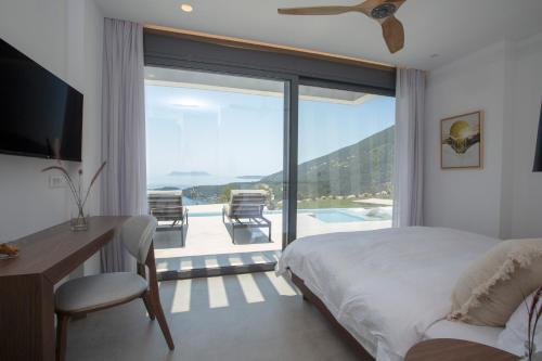 a bedroom with a bed and a desk and a balcony at Song of the Sea in Sivota