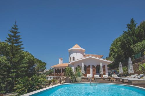 a villa with a swimming pool and a lighthouse at Villa Pietra Estoril Eco Guesthouse in Estoril