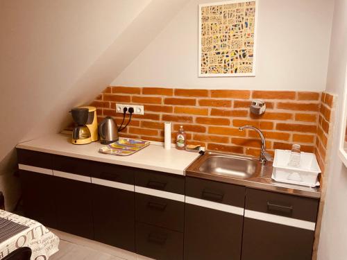 a kitchen with a sink and a brick wall at Fonfa Liget in Sénye