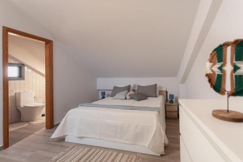 a white bedroom with a bed and a mirror at Osiris - cozy sea walk lodge with private garden in Nea Makri