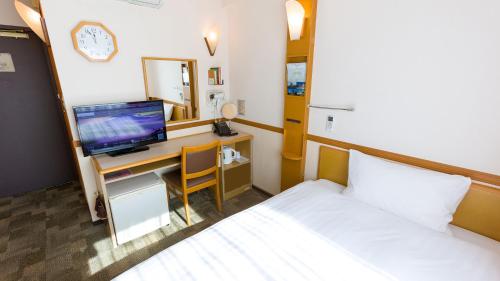 a bedroom with a bed and a desk with a television at Toyoko Inn Hokkaido Kitami Ekimae in Kitami