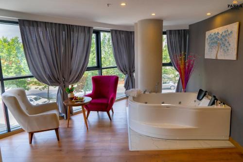 een grote woonkamer met een groot bad en stoelen bij Parla Suite Hotel in Esenyurt
